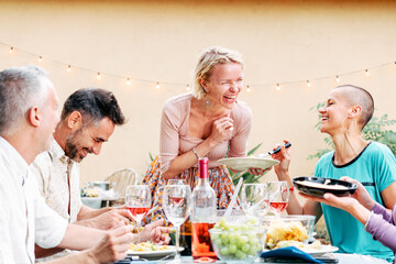 Fototapeta na wymiar Mature people celebrating a bbq party sharing his food with his friends. Pretty woman brings a salad to the table. Lifestyle concept. High quality photo