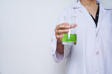 Close-up of a scientist's hand holding a flask with a green liquid isolated over white background.