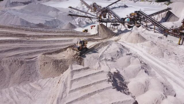 Aerial view of a mining crawler bulldozer in work in limestone quarry.