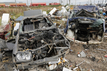 Details with destroyed cars or car parts in a makeshift scrap yard.