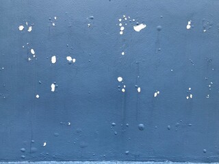 weathered facade outdoor wall. The layers of paint peeling off and showing cracked paint coating stucco. Cracks, blisters on the surface