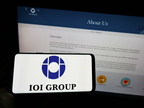 Stuttgart, Germany - 12-12-2021: Person holding mobile phone with logo of Malaysian conglomerate IOI Corporation Berhad on screen in front of web page. Focus on phone display.