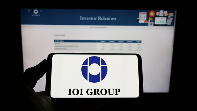 Stuttgart, Germany - 12-12-2021: Person holding cellphone with logo of Malaysian conglomerate IOI Corporation Berhad on screen in front of business webpage. Focus on phone display.