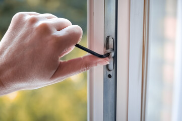 adjusting the white plastic window. a worker uses a hexagon to repair a window. 