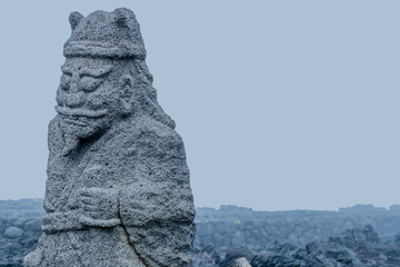 Ancient stone carved figure of sea god on coast of Jeju island, South Korea.