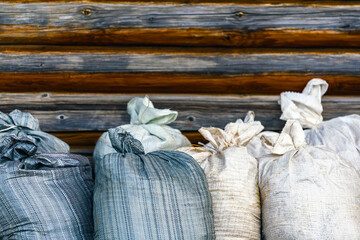A row of large bags in selective focus filled with agricultural products - hay, straw or potatoes...