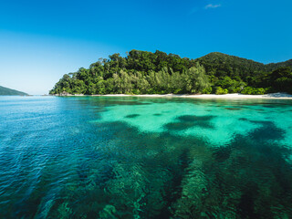 Scenic view of Koh Adang Island crystal clear turquoise sea with coral reef against summer blue sky. Near Koh Lipe Island, Tarutao National Marine Park, Satun, Thailand. Shorkeling Spot.