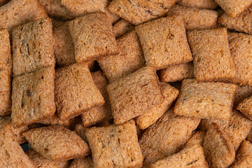 Crispy chocolate pads background macro. Cocoa cereal dessert for a fast breakfast. Morning breakfast dry chocolate pads close up. Chocolate flakes cereal pads with cream filling