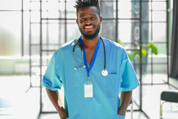 African male doctor wearing medical coat standing in hospital corridor.