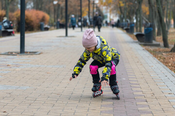 Cute little girl learns to roller skate. A child on roller skates falls