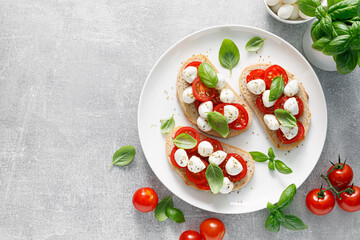 Caprese toasts with mini mozzarella cheese, cherry tomato and basil, top view - 533102092