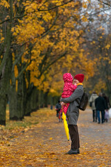 Mom holds the baby in her arms against the background of an autumn park. Walking with children....