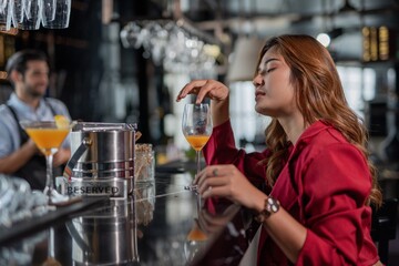 Portrait of a beautiful sexy asian woman in a sky lounge bar having a cocktail drink alone