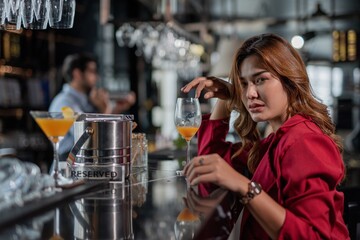 Portrait of a beautiful sexy asian woman in a sky lounge bar having a cocktail drink alone