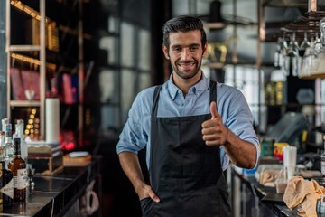 Photo of a handsome bartender doing thumb up pose behind the bar in a sky lounge bar in Bangkok