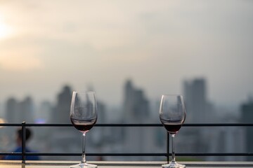 Photo of a pair of wineglasses with the background of sunset and Bangkok skyline