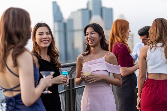 Photo of a group of young elegant businesswomen mingle with each other drinking wine and champagne on a rooftop bar celebrating the successful of company latest deal and hit target goal of the year