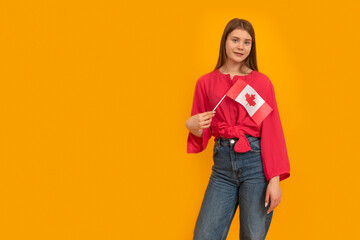 Young woman holds the flag of Canada in bright yellow background. Study in Canada. Student exchange...