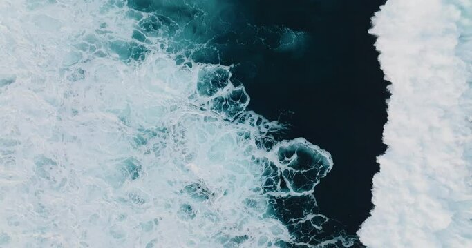 Top down aerial view of beautiful giant blue ocean waves crashing and foaming with white wash background 