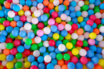 Fototapeta na wymiar Multi colored, highly saturated plastic balls, in soft play ball pit, at a child's play park. Colorful balloon.