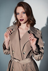 Fototapeta premium Film noir style: charming elegant woman. Vintage (retro) portrait of smiling young girl in trench coat