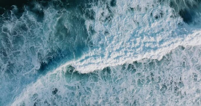 Top down aerial view of beautiful giant blue ocean waves crashing and foaming with white wash background 