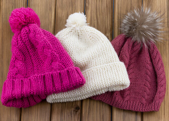 Fototapeta na wymiar Set of colored knit wool hat with pom pom on wooden background