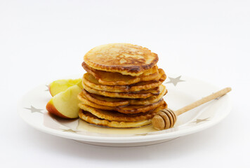 Stack of pancakes with apple slices and honey on the plate on white background