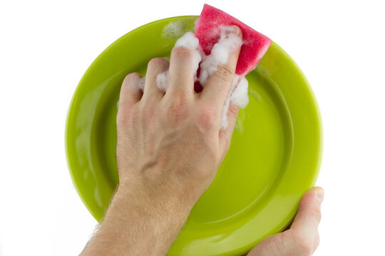 Housekeeping concept. Hand with red sponge washing green plate isolated on white background