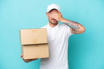 Delivery caucasian man isolated on blue background covering eyes by hands. Do not want to see...