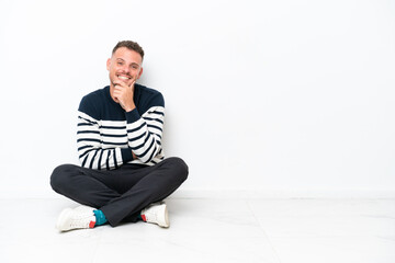 Young man sitting on the floor isolated on white background smiling