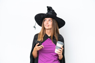 Young caucasian woman costume as witch isolated on white background holding coffee to take away and a mobile while thinking something