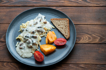 spaghetti with sauce, tomatoes and bread in a gray plate. light breakfast concept. cooked pasta with vegetables and mayonnaise