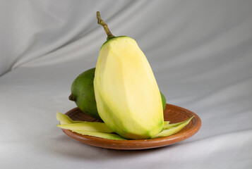 peeled green mango on clay plate.