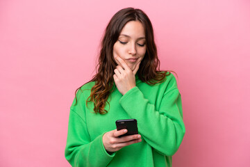 Young caucasian woman isolated on pink background thinking and sending a message