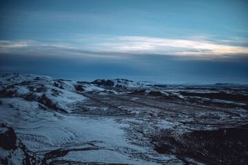 Iceland blue hour with light yellow clouds over winter mountain landscape with snow