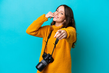 Young photographer woman isolated on blue background making phone gesture and pointing front