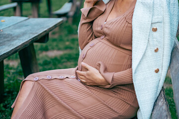 Fototapeta premium Pregnant woman sitting on a bench in nature park. relaxing and enjoy in fresh air.