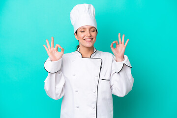 Young caucasian chef woman isolated on blue background in zen pose