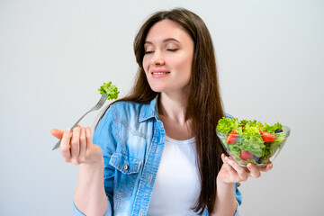 Beautiful young woman eats salad with lettuce, tomato and olives. Healthy lifestyle