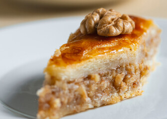 Traditional arabic dessert baklava and walnuts in white plate with a cup of coffee or tea  .Homemade baklava with nuts and honey.