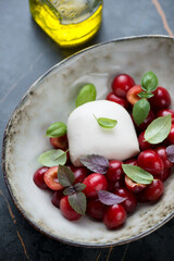 Bowl with mozzarella cheese, sliced sweet cherry and fresh basil leaves, vertical shot, selective focus, middle close-up