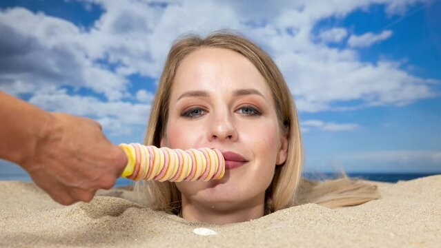 Woman buried in sand on beach licking a lolly