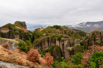 Fototapeta na wymiar Panoramic morning view of unique rock formations near tourist village Kastraki on cloudy day in Kalambaka, Meteora, Thessaly, Greece, Europe. Rocks are overgrown with green moss. Moody atmosphere