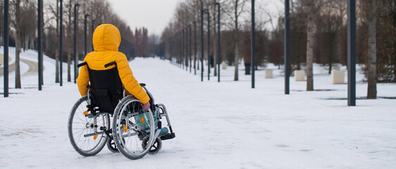 Woman in wheelchair relaxing in winter park. 