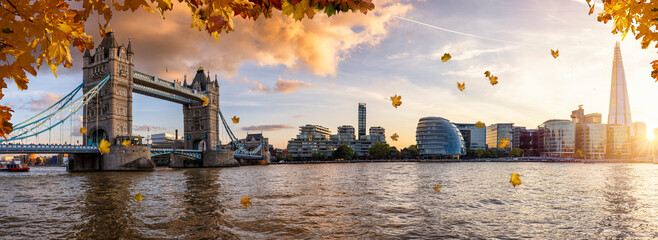 Panoramic view of the London city skyline during beautiful autumn time with golden leaves falling from the trees and warm sunshine colors