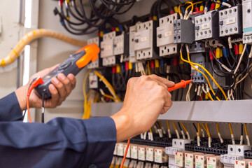 Electrical engineer using measuring equipment to checking electric current voltage at circuit breaker and cable wiring system , Electrical service concept .