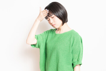 発熱で額に手を当てている若い女性