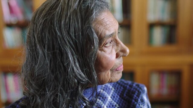 Thinking, retirement and senior woman in library or home looking out window. Memories, nostalgia and thoughtful grandma with life experience. Health, memory and an elderly lady with wrinkles on face.