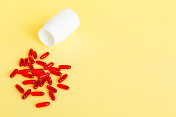 Red pills spilled around a pill bottle. Medicines and prescription pills flat lay background. Red...